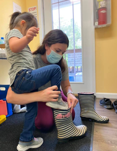 Occupational Therapist helping a girl put her boots on at Sumlar Therapy Services, Inc