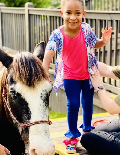 Girl petting a horse at Sumlar Therapy Services